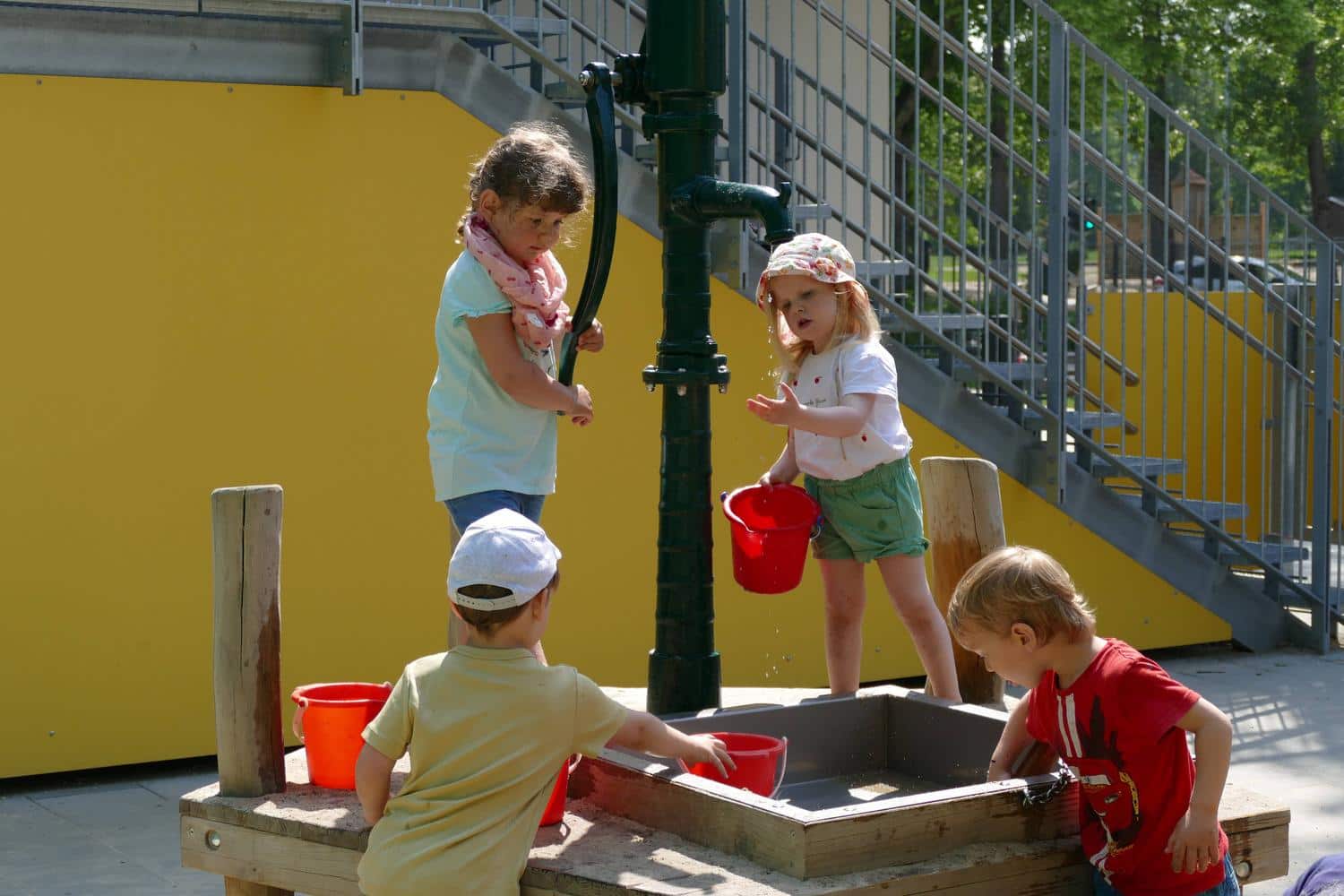Kinder schoepfen Wasser aus einem Brunnen