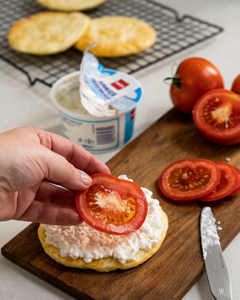 Auf diesem Bild siehst du wie das Wolkenbrot mit Tomatenscheiben belegt wird.