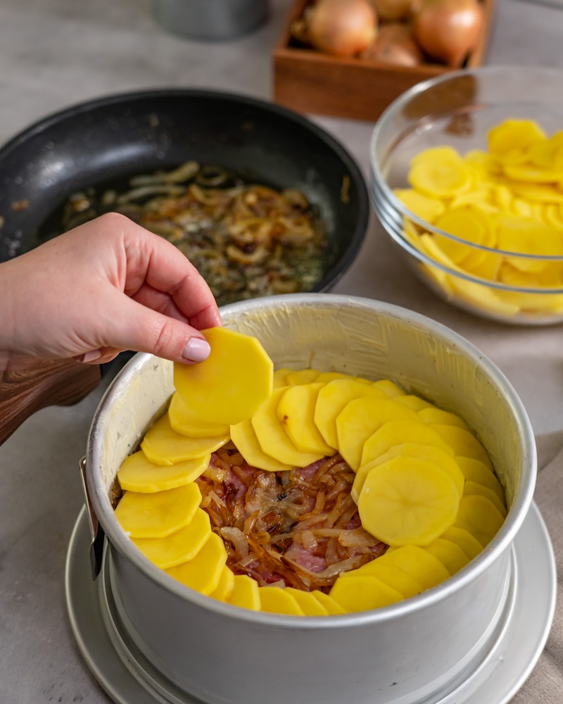 Dieses Bild zeigt wie Kartoffelscheiben in die Springform gelegt werden.