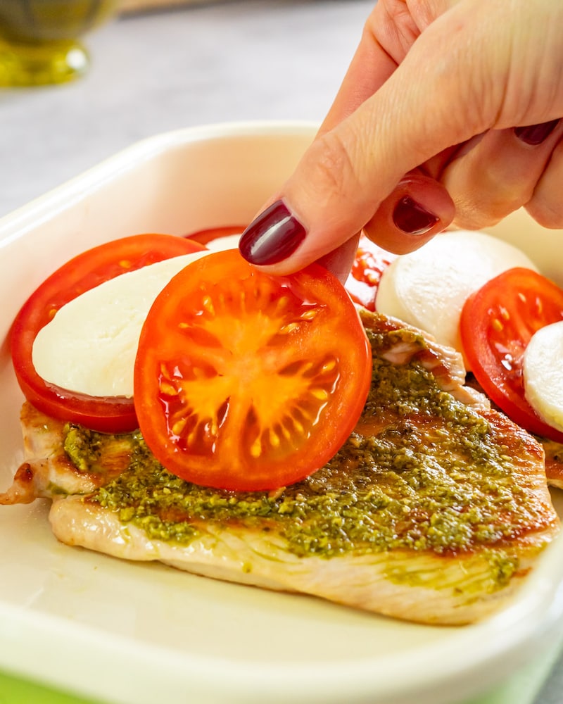 Dieses Bild zeigt wie die Tomaten und Mozzarella Fächer-artig auf das Putenschnitzel gelegt wird.