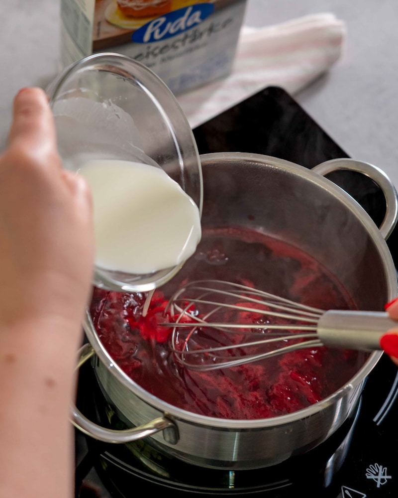Diese Bild zeigt wie die Milch zu den Himbeeren in den Topf kommt.
