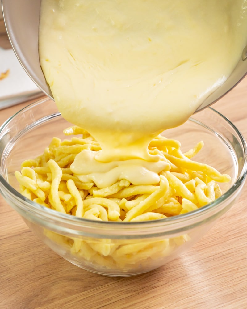 Dieses Bild zeigt wie die Sauce über die Spätzle gegeben wird.