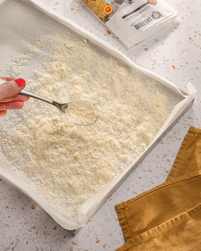 Dieses Bild zeigt wie der Parmesan auf dem Blech verteilt wird.