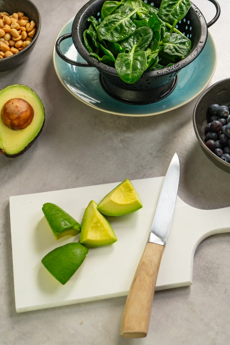 Dieses Bild zeigt die geschnittene Avocado und den gewaschenen Baby-Spinat.