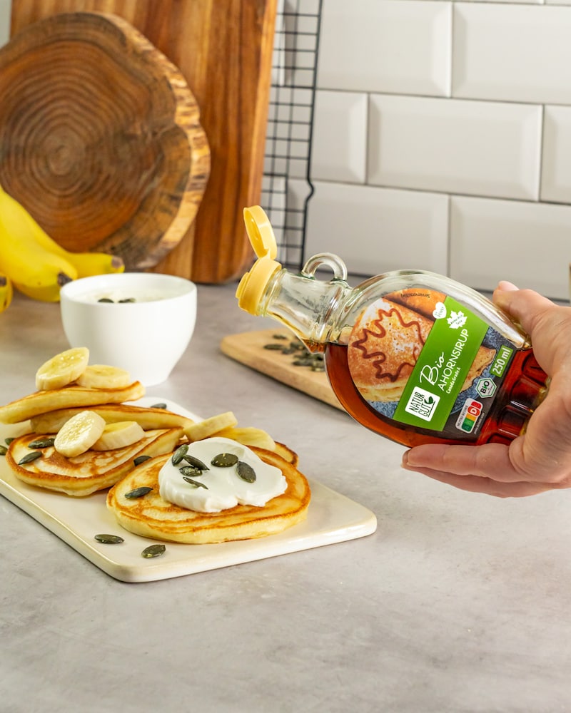 Dieses Bild zeigt wie der Ahornsirup auf die Pancakes gegeben wird.