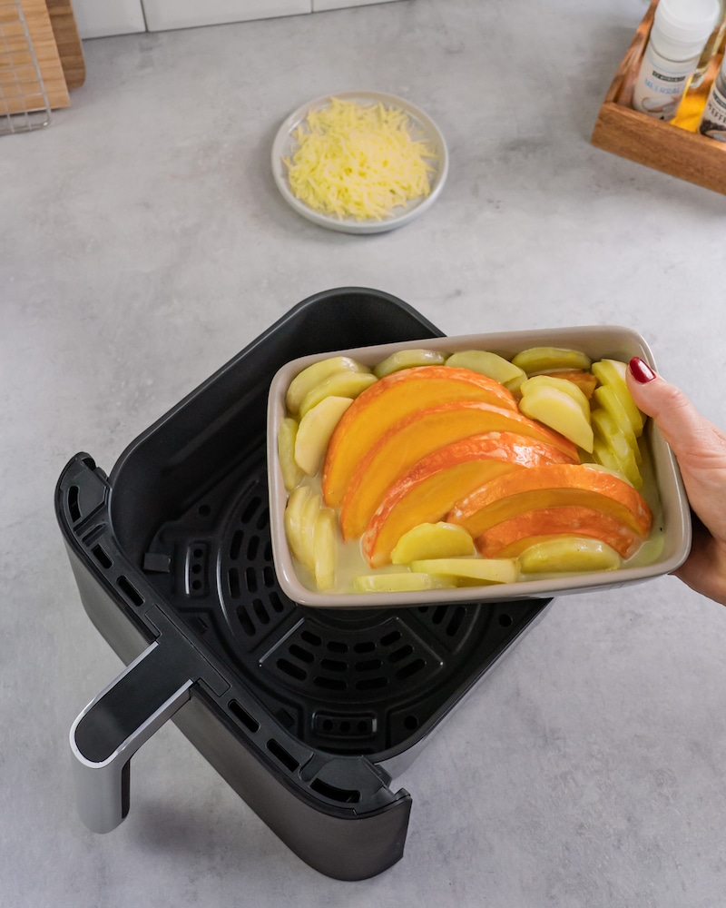 Diese Bild zeigt wie die Auflaufform in die Heißluftfritteuse gegeben wird.