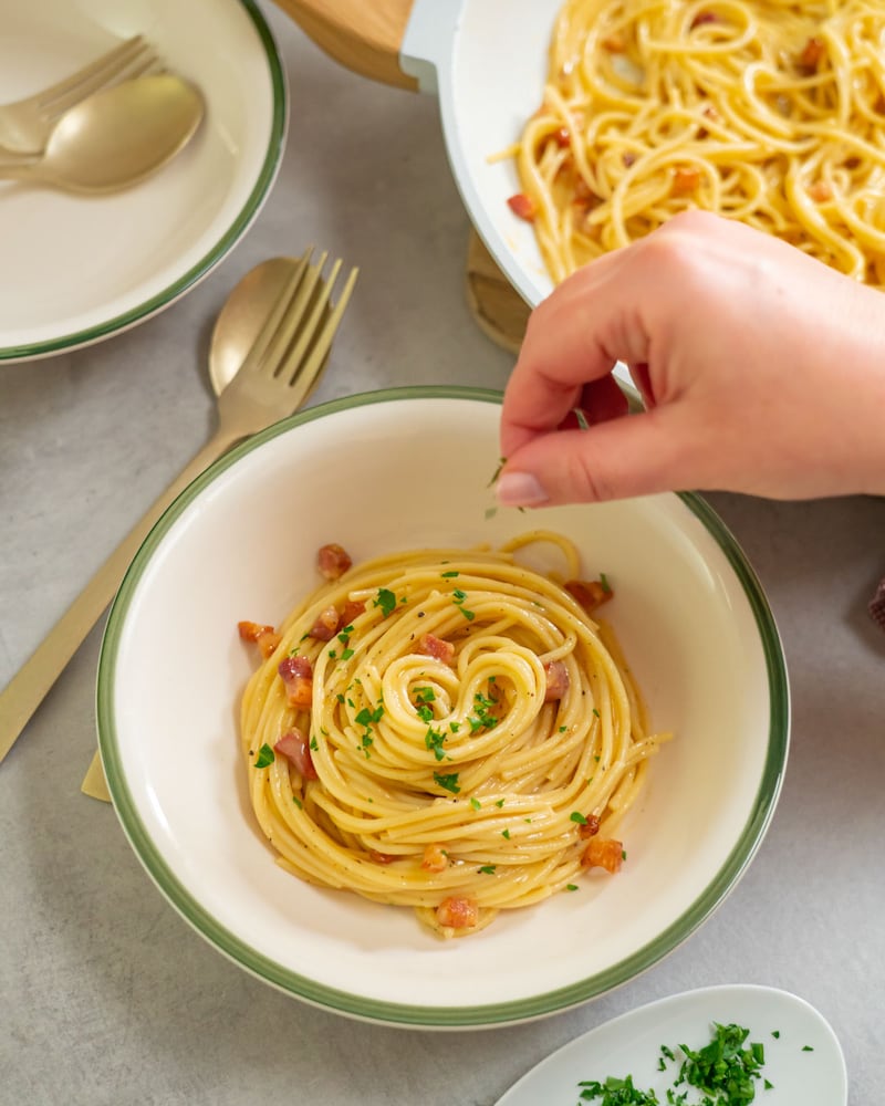 Diese Bild zeigt das Garnieren der Spaghetti Cabonara.