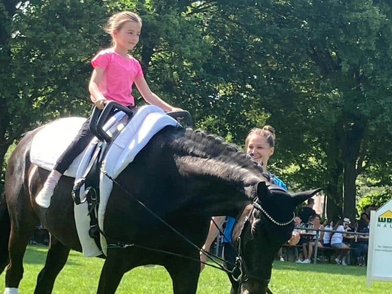 Ein Maedchen beim Reiten auf einem Pferd