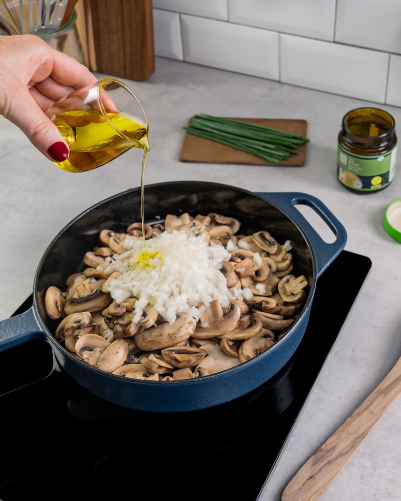 Diese Bild zeigt wie die Pilze mit den Zwiebeln und Knoblauch in Olivenöl gebraten werden.
