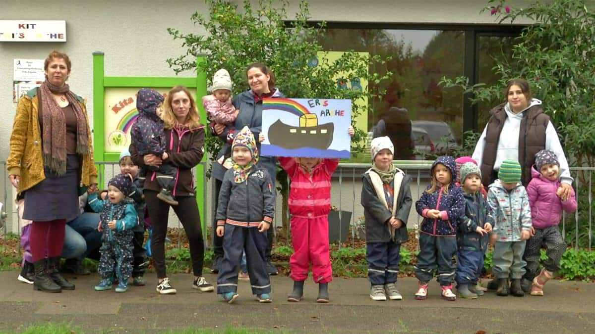 Vereinsmitglieder und Kinder lachen mit selbstgemaltem Bild in die Kamera