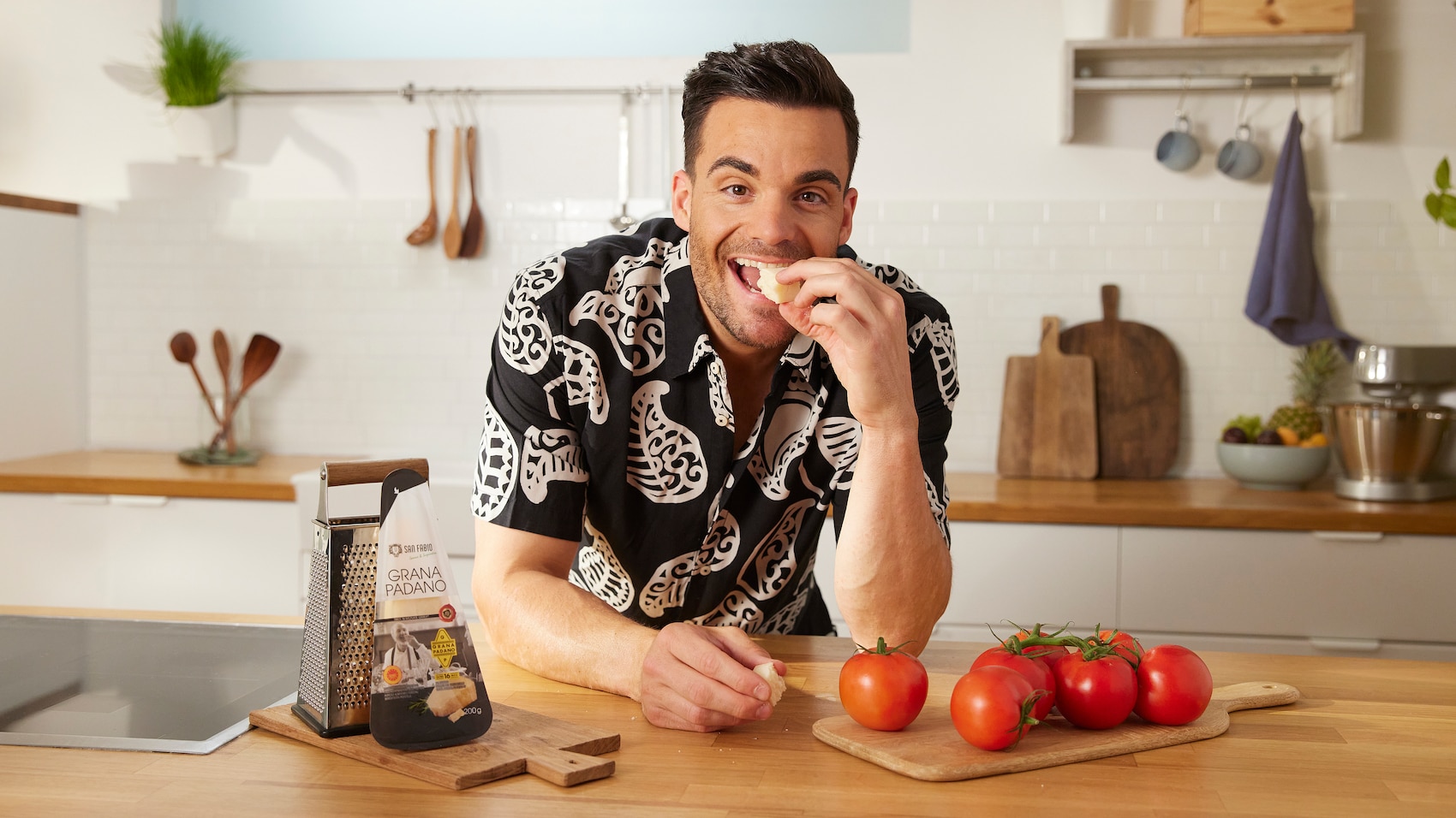 Tomaten sind im Vorgergrund und Stefano Zarrella beißt in einen Käse.