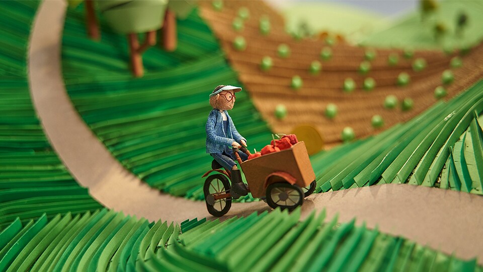 Mann auf Lastenfahrrad mit Äpfeln aus Papier