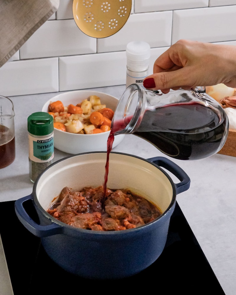 Diese Bild zeigt wie das Fleisch mit Rotwein abgelöscht wird.