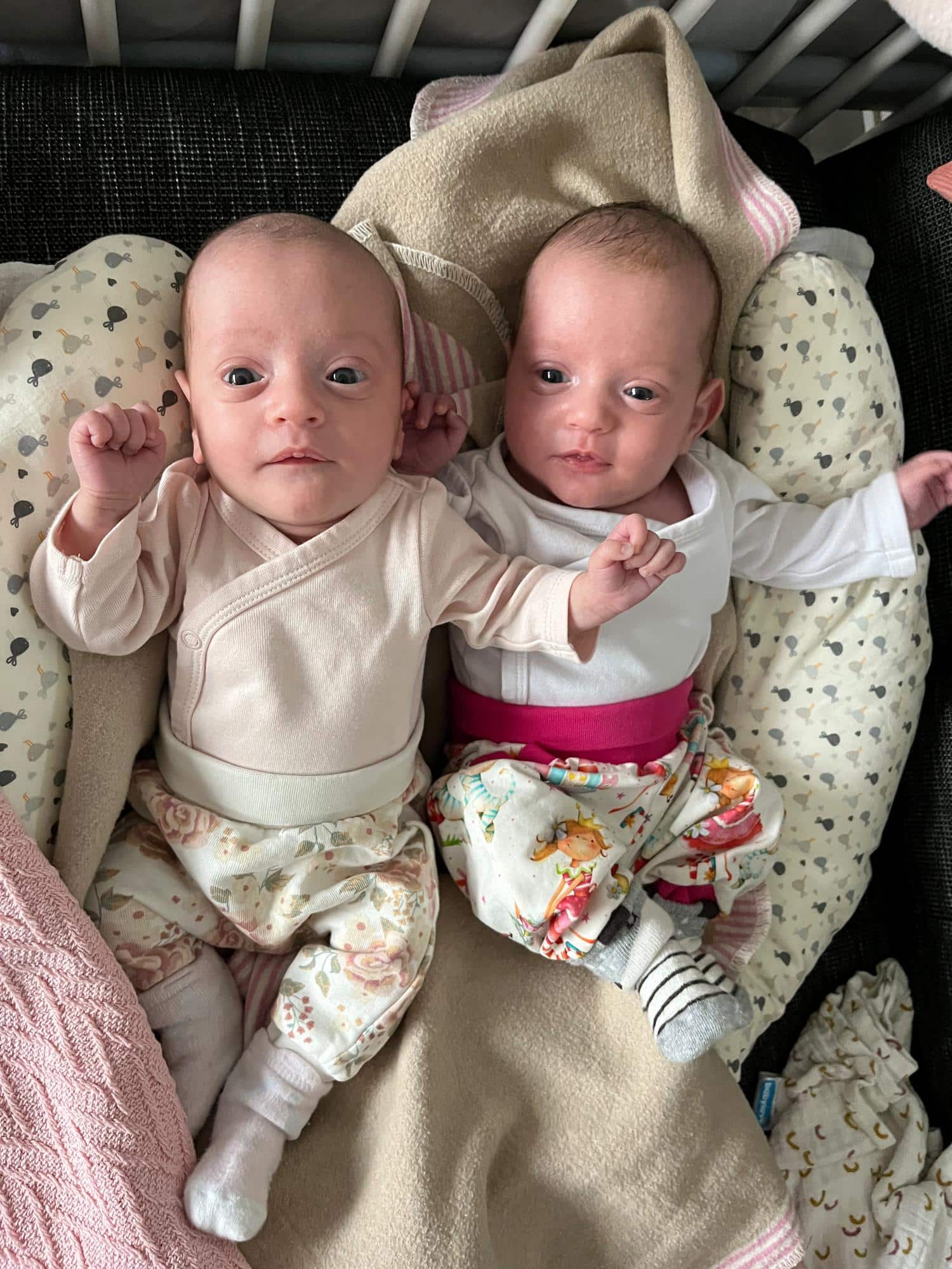 Zwei Babys liegen nebeneinander auf Decken