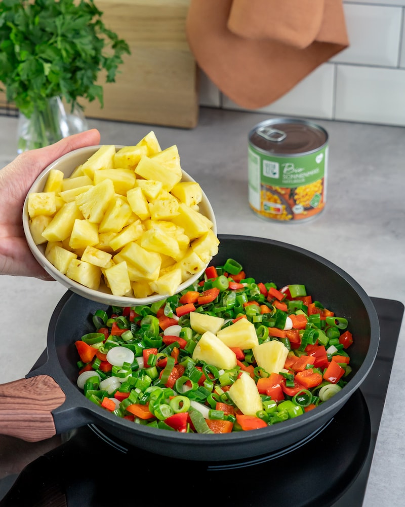Dieses Bild zeigt wie die Ananas zu dem restlichen Gemüse gegeben wird.