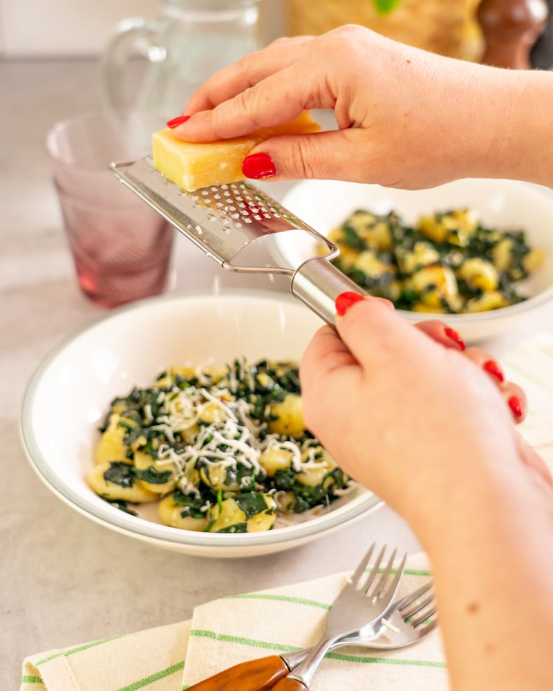 Dieses Bild zeigt wie der Parmesan hinzugegeben wird.