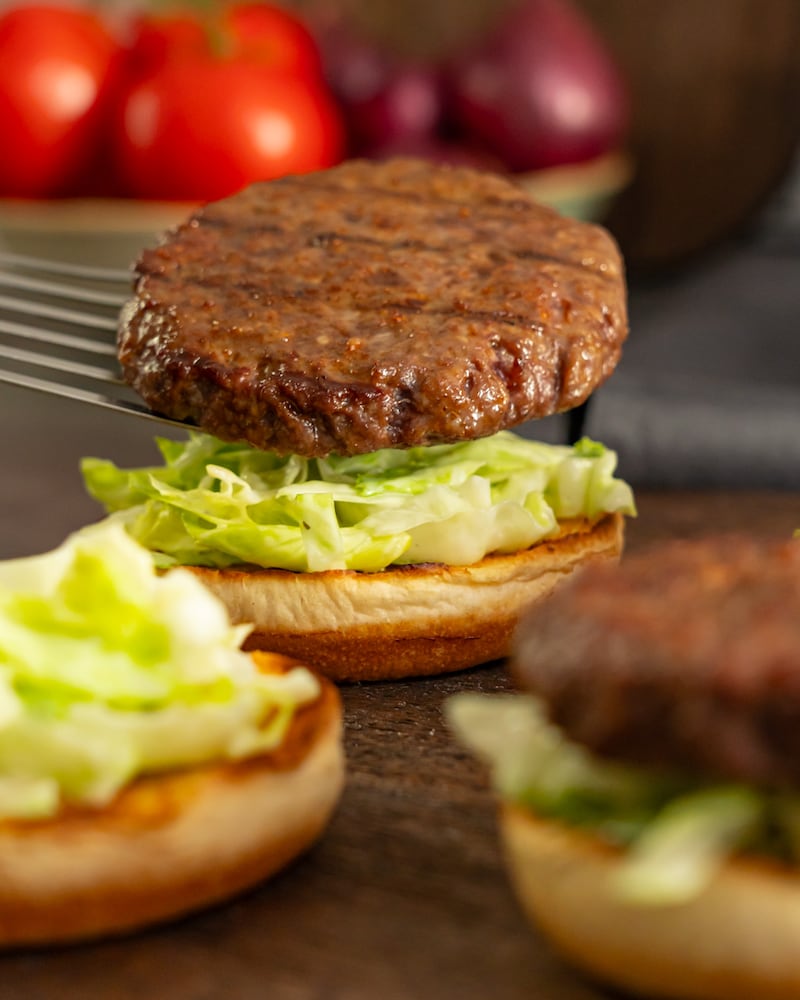 Dieses Bild zeigt wie das Pattie auf den Burger gegeben wird.