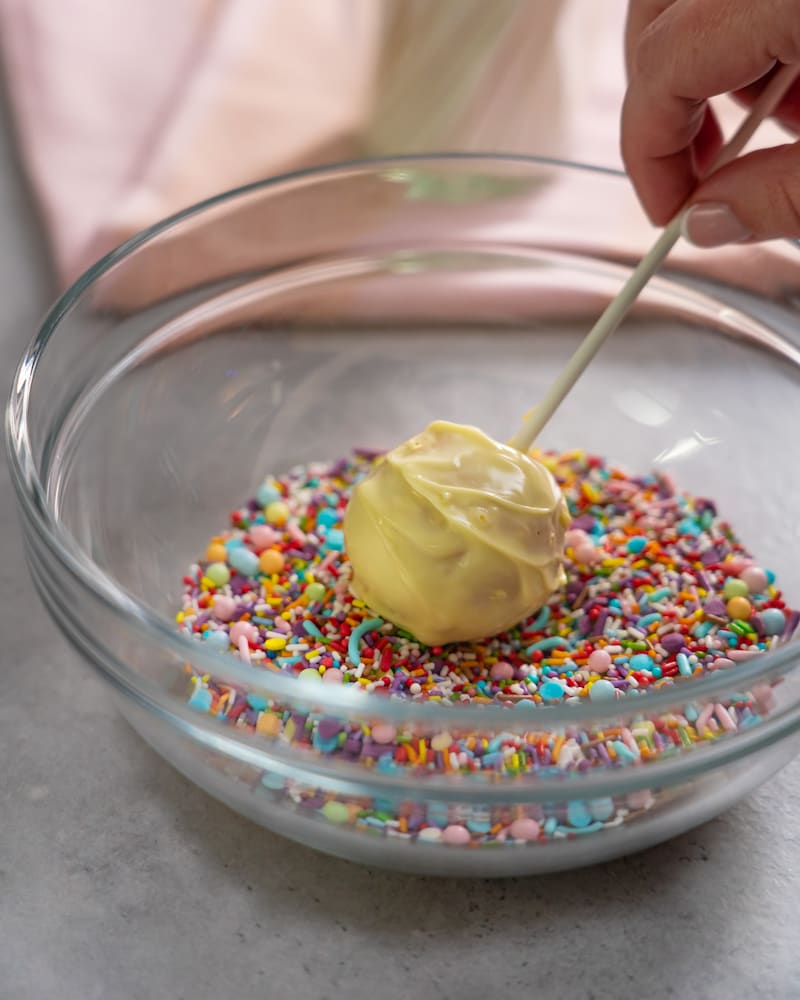 Dieses Bild zeigt wie Streusel auf die Cake-Pops gegeben werden.
