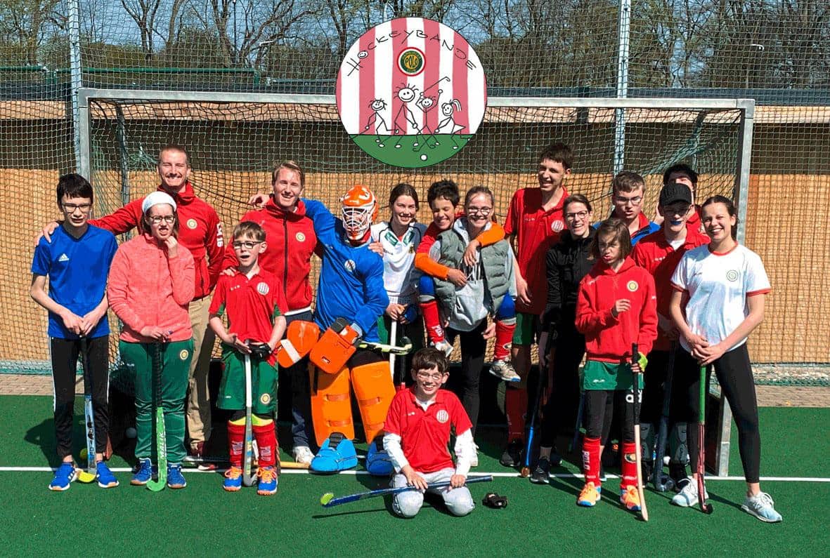 Kinder und Vereinsmitglieder stehen auf dem Spielfeld und laecheln in die Kamera