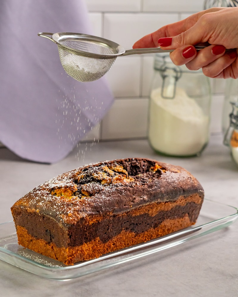 Dieses Bild zeigt wie Puderzucker über den Kuchen gegeben wird.