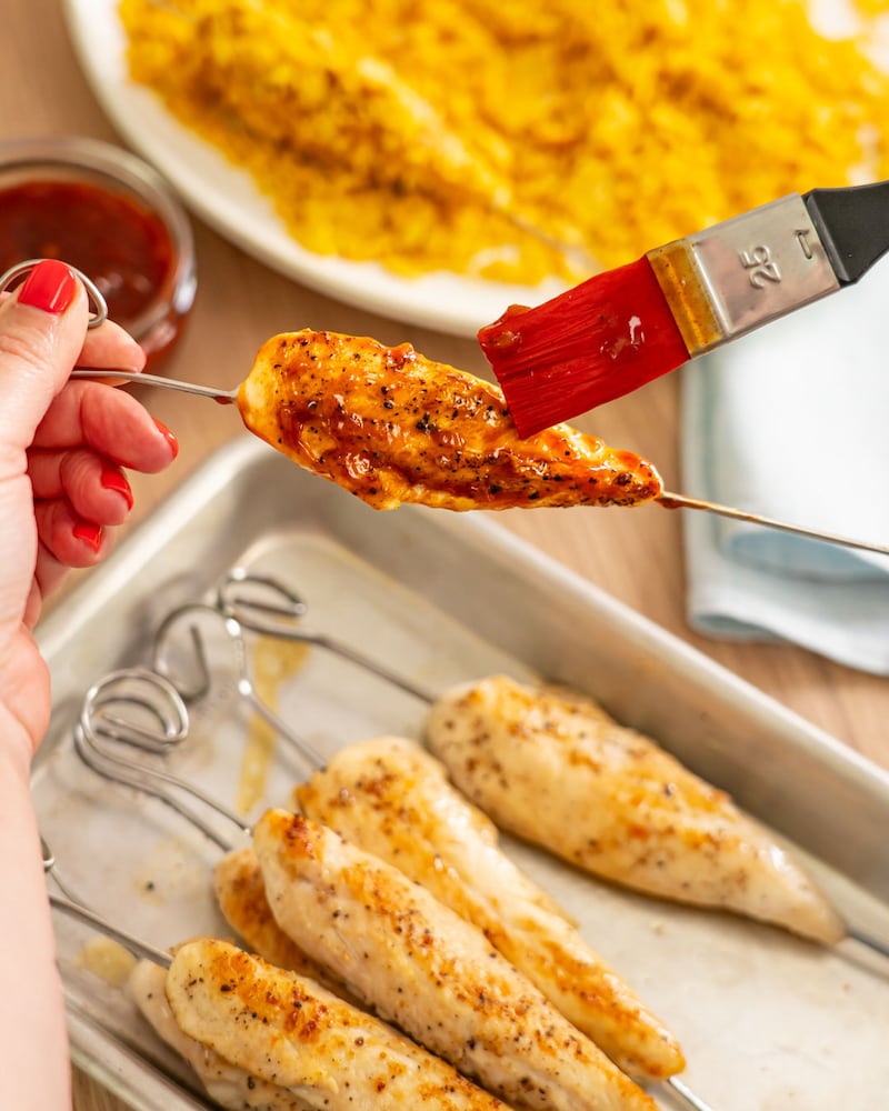 Dieses Bild zeigt wie die Chicken Spieße mit BBQ-Soße bestrichen werden.