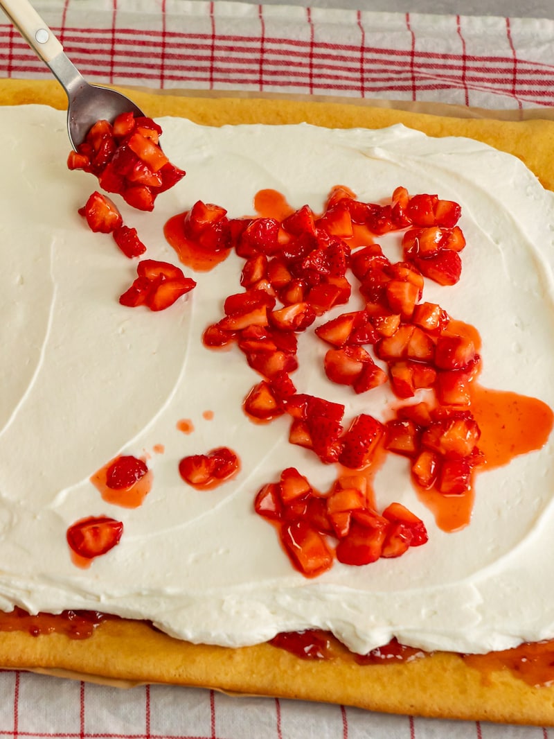 Dieses Bild zeigt wie der Biskuit mit Marmelade und Erdbeeren gefüllt wird.