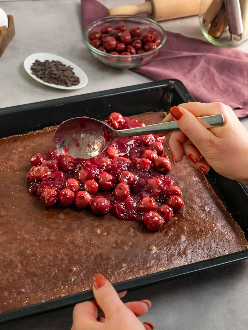 Dieses Bild zeigt wie die Kirschen auf den Kuchen gegeben werden.