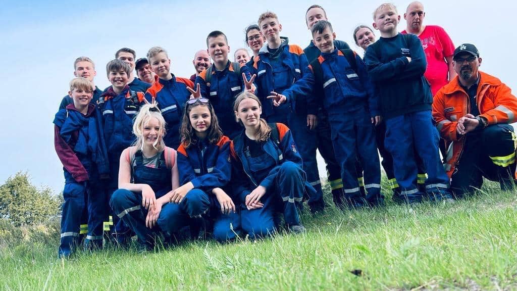 Kinder und Vereinsmitglieder in Uniform laecheln in die Kamera