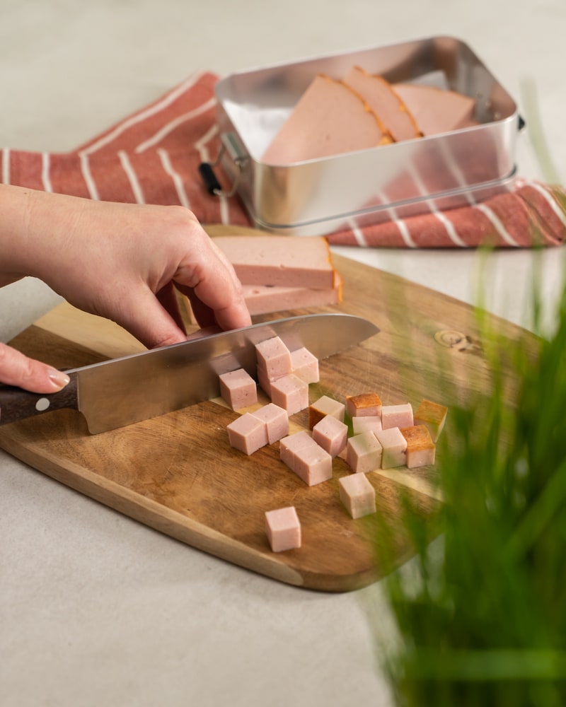 Auf diesem Bild siehst du wie Leberkäse geschnitten wird.