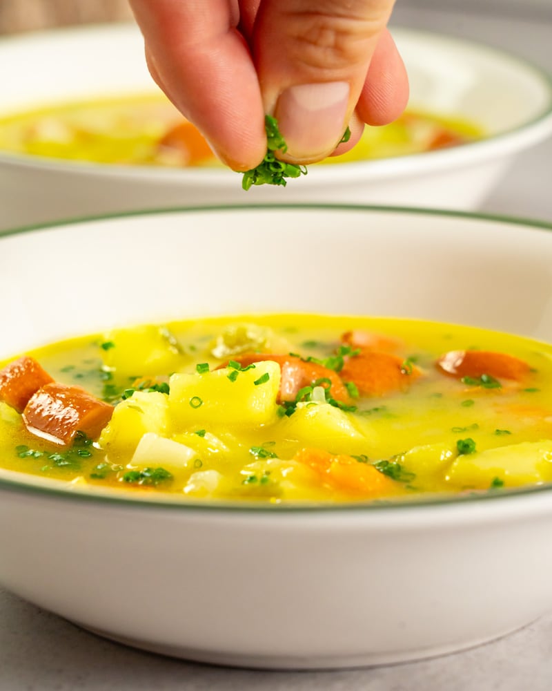 Dieses Bild zeigt wie die Kräuter auf die Suppe gegeben werden.