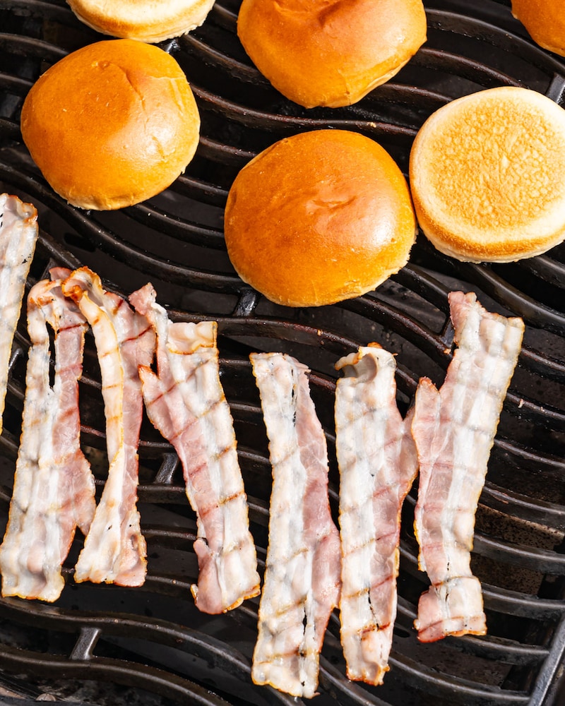 Dieses Bild zeigt den Bacon und die Burger-Buns auf dem Grill.