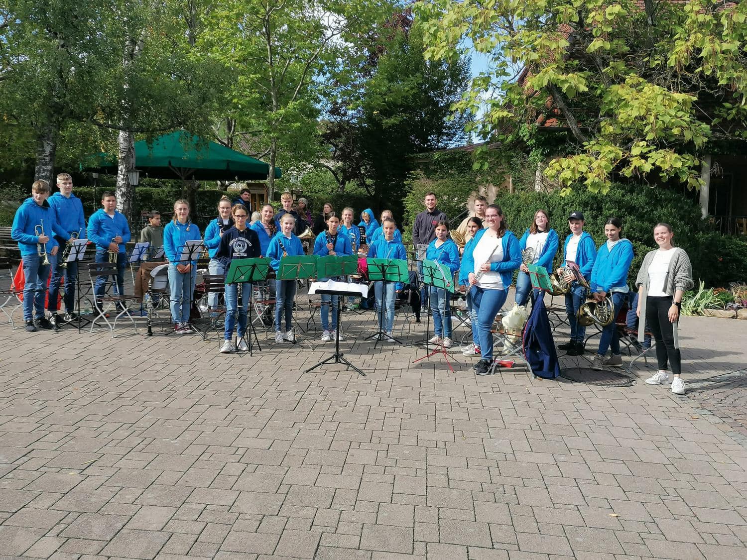 Kinder und Vereinsmitglieder laecheln mit Instrumenten in die Kamera