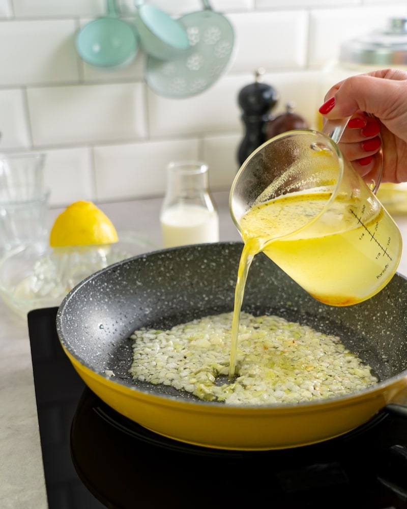 Dieses Bild zeigt wie die Zwiebeln und Knoblauch mit Brühe abgelöscht werden.