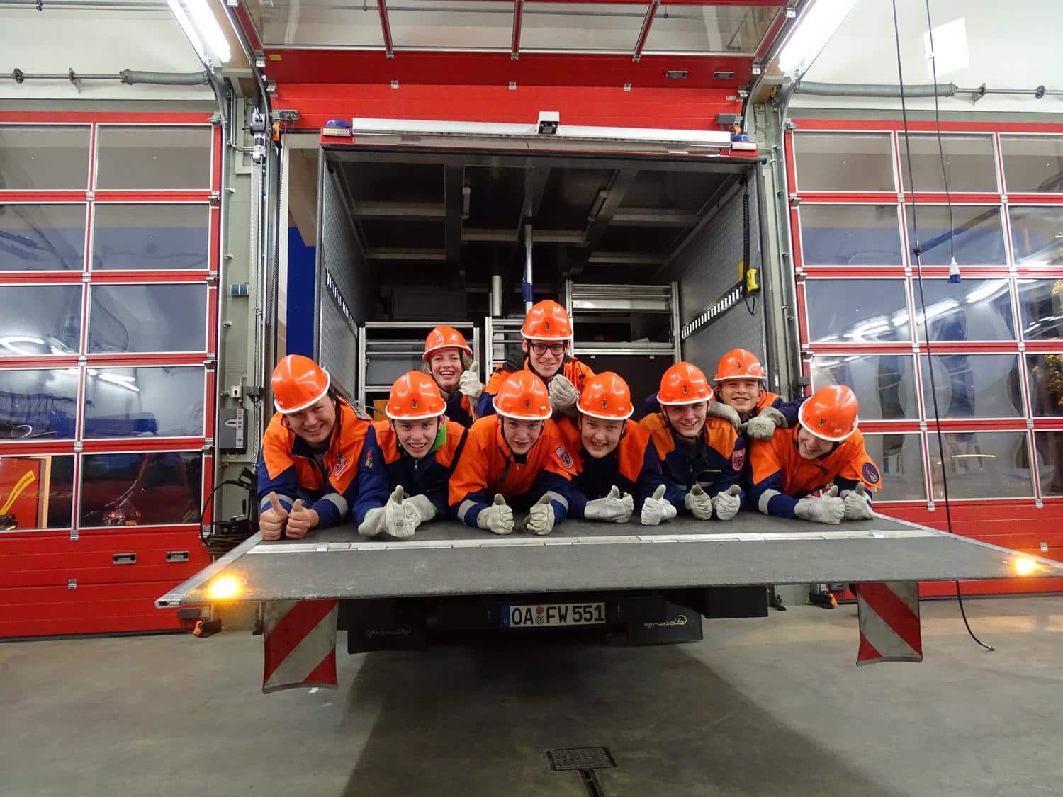 Vereinsmitglieder liegen in einem Feuerwehrwagen und laecheln in die Kamera