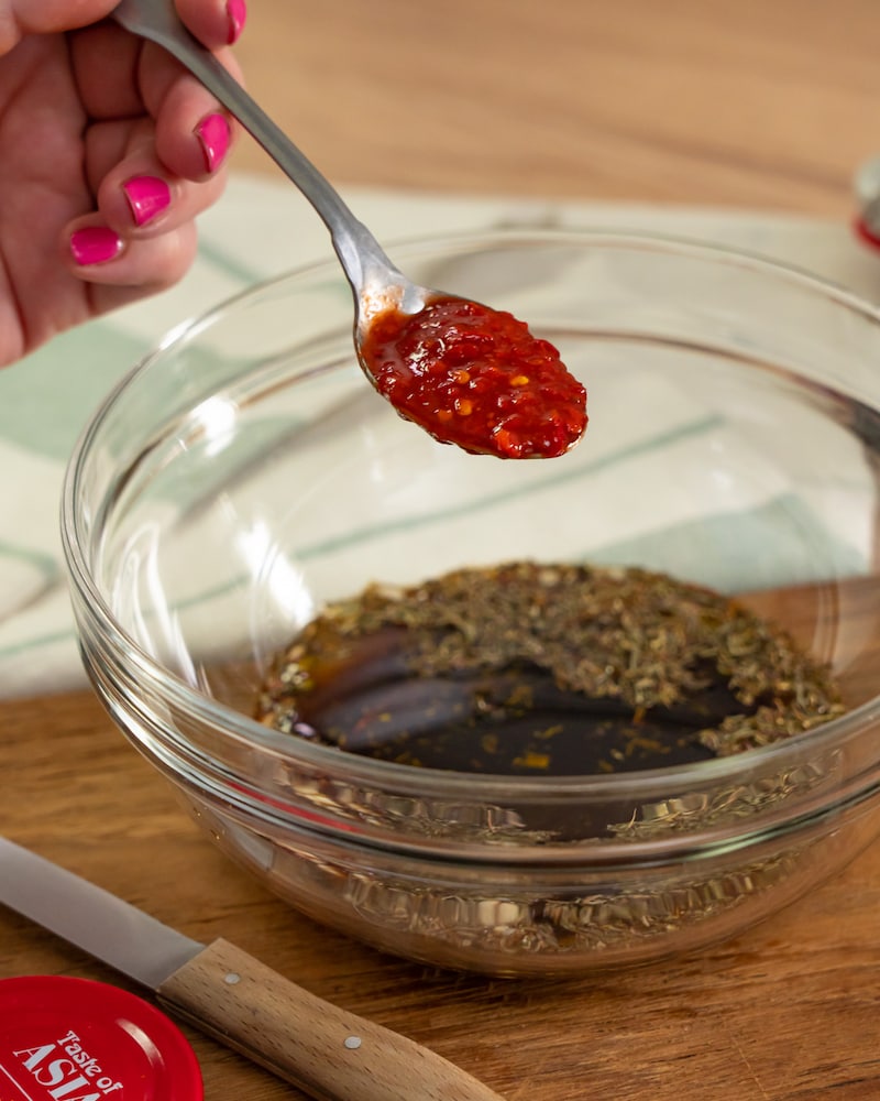 Dieses Bild zeigt, wie Sambal Oelek hinzugefügt wird.