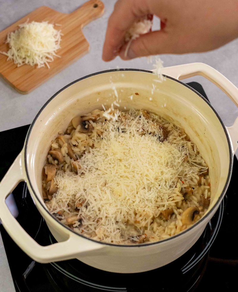 Dieses Bild zeigt, wie das Risotto mit Käse bestreut wird.