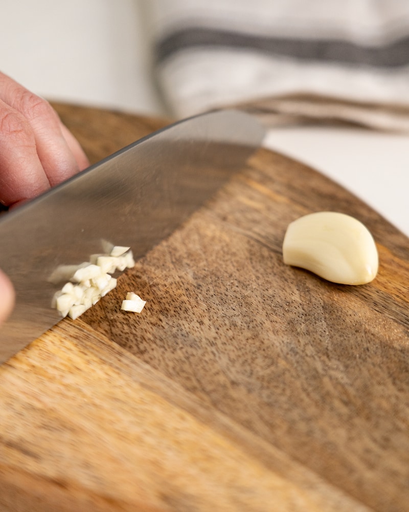 Auf diesem Bild siehst du wie Knoblauch klein gewürfelt wird.