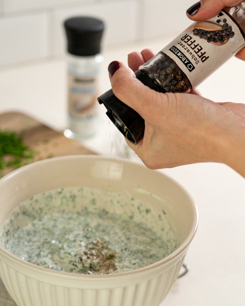 Auf diesem Bild siehst du wie die Creme mit Salz und Pfeffer abgeschmeckt wird.
