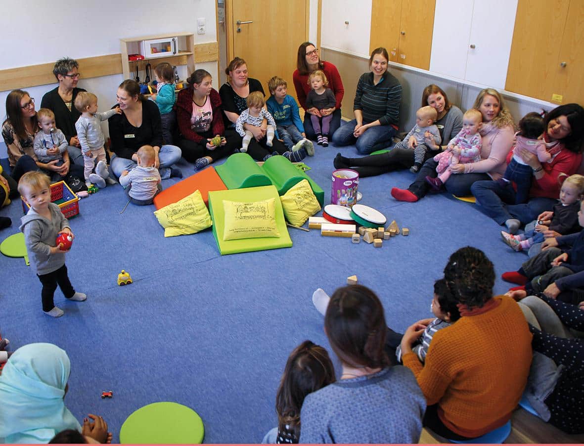 Muetter und Kinder spielen im Sitzkreis