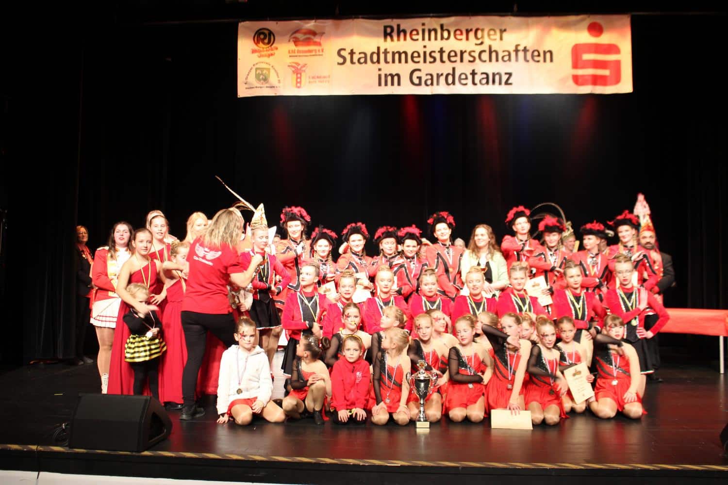 Die Gruppe posiert mit einem Pokal auf der Bühne