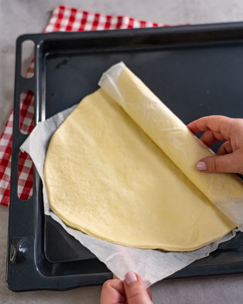 Dieses Bild zeigt wie der Pizzateig ausgerollt wird.