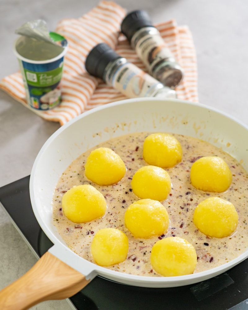 Dieses Bild zeigt das hinzugeben der Kartoffelklöße in der Speck Sauce.