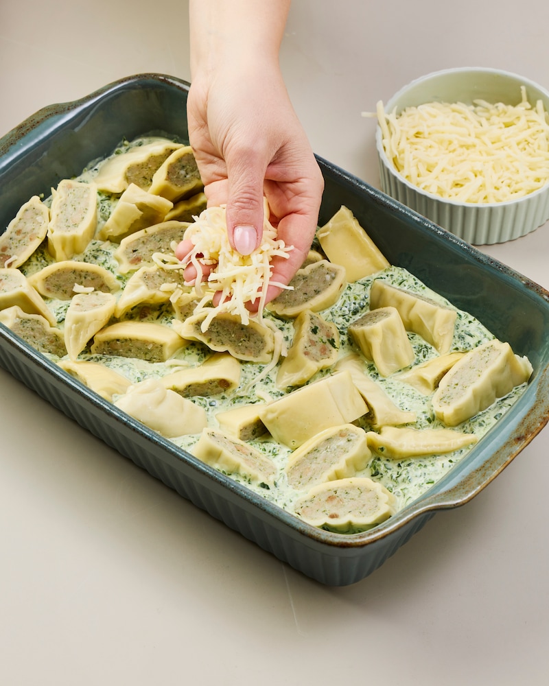 Dieses Bild zeigt, wie der Käse über allem verteilt wird.