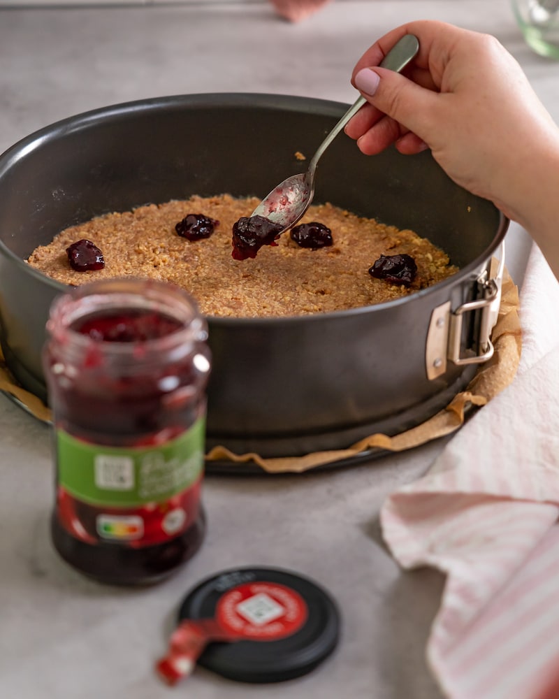 Dieses Bild zeigt wie Marmelade auf den Kuchenboden gegeben wird.