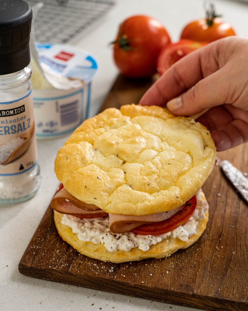 Auf diesem Bild siehst du wie eine Scheibe Wolkenbrot obendrauf gelegt wird.