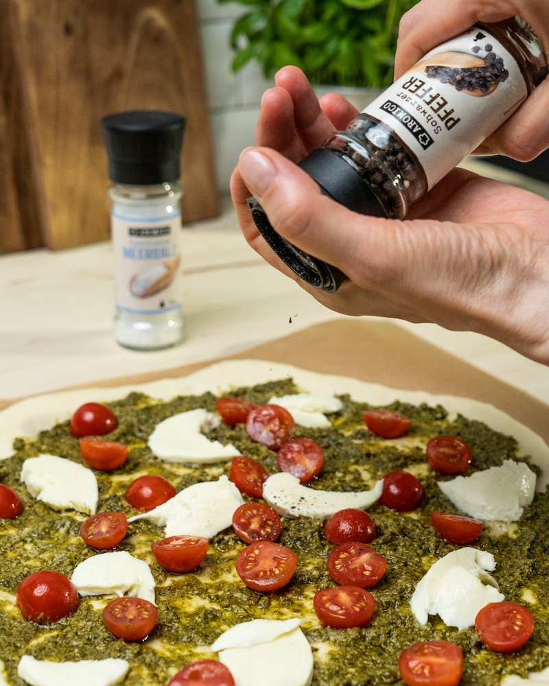 Auf diesem Bild siehst du wie die belegte Pizza belegt wird.