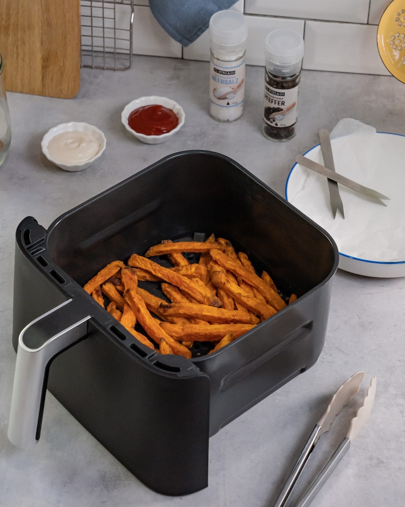 Dieses Bild zeigt wie die Süßkartoffelpommes aus dem Airfryer kommen.