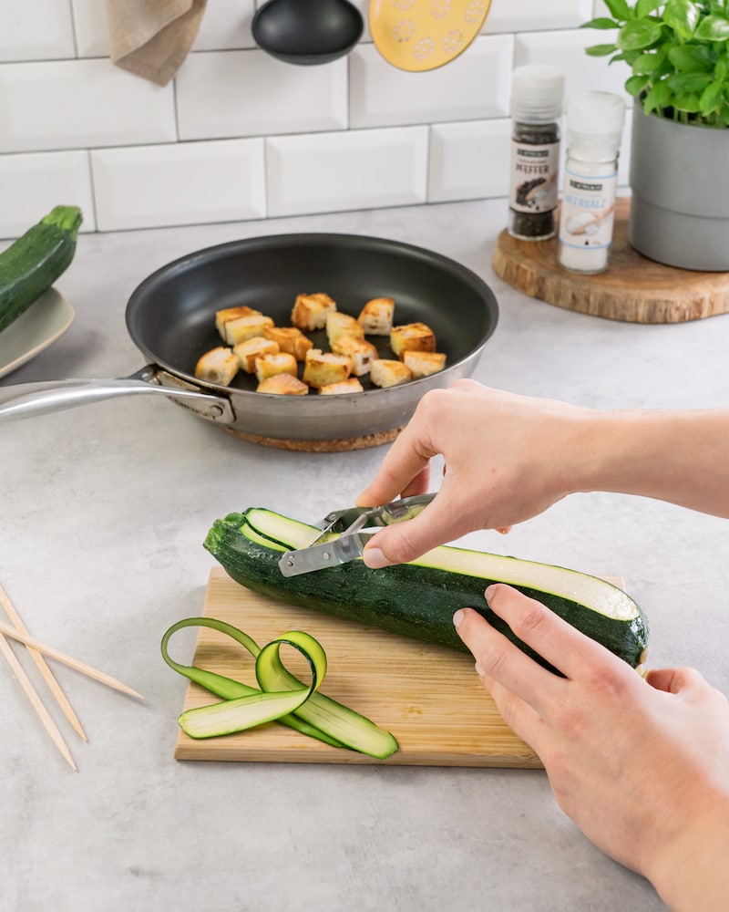 Dieses Bild zeigt wie die Zucchini in Scheiben geschält wird.