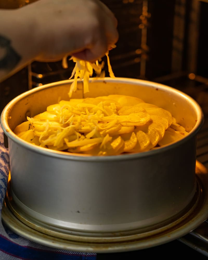 Dieses Bild zeigt wie Käse auf den Kuchen gegeben wird.