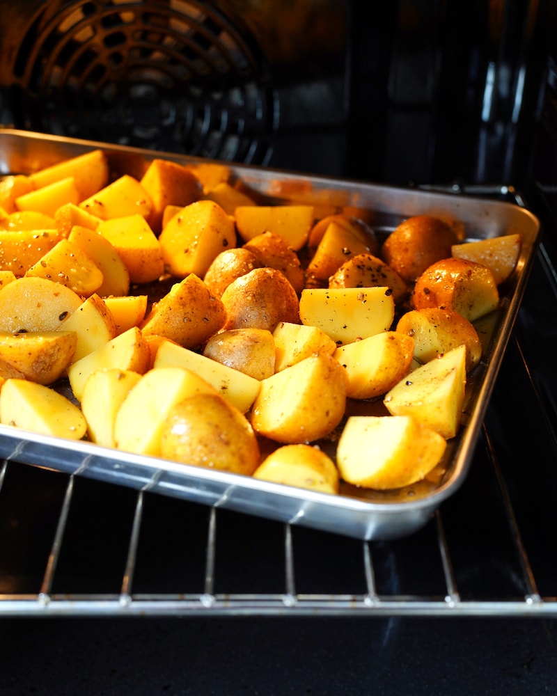 Dieses Bild zeigt wie die Kartoffeln in den Ofen gegeben werden.